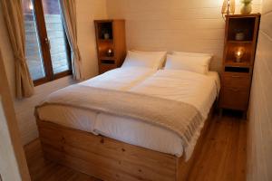 a bedroom with a large bed with white sheets at Chalet in de Ardennen Comfort & Stilte The Wood in Amblève