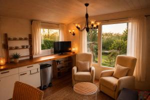 a kitchen with two chairs and a tv and two windows at Chalet in de Ardennen Comfort & Stilte The Wood in Amblève