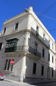 a white building with a balcony on the side of it at Corner Hostel in Sliema