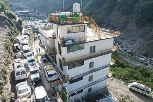 a building on the side of a mountain with cars parked at Hotel Uday Villa in Kharsālī