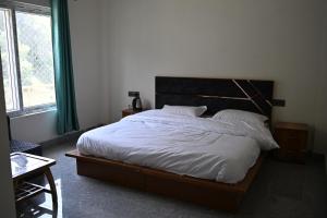 a bedroom with a large bed with white sheets and pillows at Hotel Uday Villa in Kharsālī +4 photos