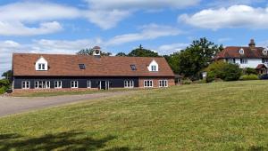 a large house with a brown roof on a field at The Clock House in Sacomb
