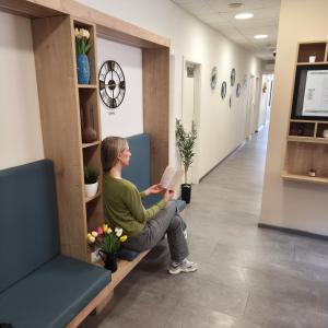 a woman sitting on a bench reading a book at Hostel Petra Marina in Dubrovnik