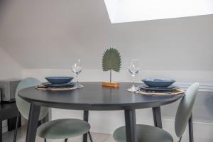 a black dining room table with two glasses and a plant at Logement entier suite balnéo privée in Vierzon
