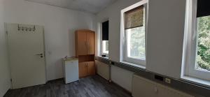 an empty kitchen with two windows and a refrigerator at Ferienwohnung in Georgenthal in Georgenthal +20 photos