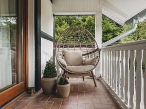 a porch with a rattan chair and two potted plants at Feriendorf Falkenegg in Lennestadt