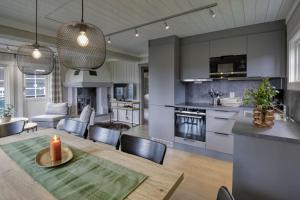 a kitchen and living room with a dining table with a candle at Hytter og leiligheter i Kvitfjell - Alpinco in Ringebu
