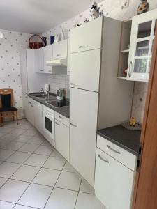 a white kitchen with white cabinets and a sink at Ferienwohnung mit Terrasse Ettringen in Ettringen