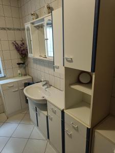 a white bathroom with a sink and a mirror at Ferienwohnung mit Terrasse Ettringen in Ettringen