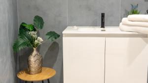 a bathroom with a white sink and a vase with flowers at Aetna LuxurySuites in Catania +111 photos