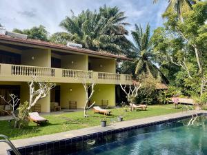 a house with a swimming pool next to a resort at Muthukirula Resort in Aluthgama