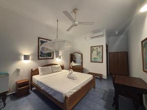 a bedroom with a bed and a desk and a ceiling fan at Muthukirula Resort in Aluthgama