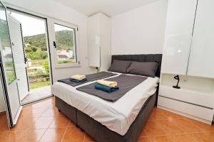 a bedroom with a large bed and a large window at Dzon Beachside Apartments in Vinišće