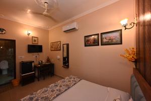 a bedroom with a bed and a desk and a television at Ardas Villa Bikaner - Heritage Luxury Boutique Stay, With Free Pick Up and Drop in Bikaner