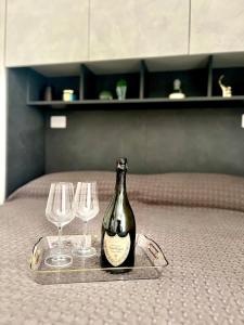 a bottle of champagne and two wine glasses on a bed at Garibaldi Living - Centro Storico Parma in Parma