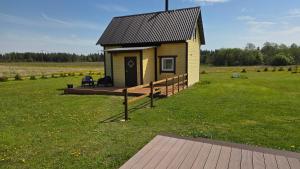 a small house in a field with a wooden deck at Peeduland Cabin in Kohatu +6 photos