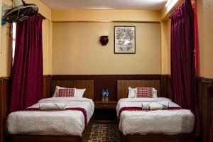 two beds in a room with red curtains at Hotel Terracotta in Bhaktapur +115 photos