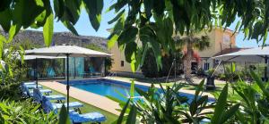 a pool with chairs and umbrellas next to a house at Mas Solana in Huércal-Overa