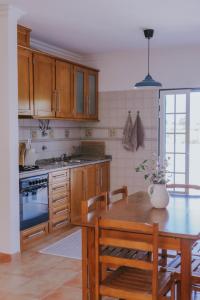 a kitchen with wooden cabinets and a wooden table at Casa do Mar - Almograve - Magnífico terraço com vista para o campo in Almograve +31 photos