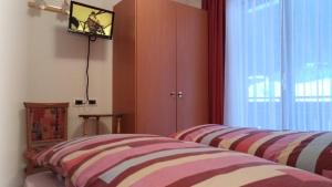a bedroom with a striped bed and a window at Appartamenti Ciesa Padon in Rocca Pietore
