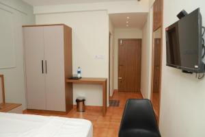 a bedroom with a bed and a tv and a chair at Arma Residency Kannur in Kannur