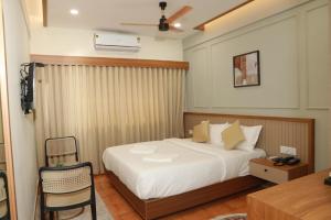 a bedroom with a bed and a table and a chair at Arma Residency Kannur in Kannur