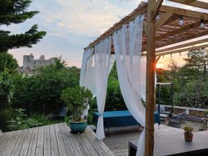 a wooden deck with a pergola with white curtains at Maison centre-ville, Vue château, Hellfest, Clisson in Clisson