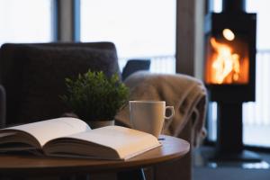 a table with an open book and a coffee cup on it at Hytter og leiligheter i Kvitfjell - Alpinco in Ringebu