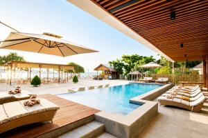 a swimming pool with lounge chairs and an umbrella at MAHAMAYA Gili Meno in Gili Meno