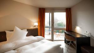 a bedroom with a bed and a desk and a balcony at Hotel Seepark Thun in Thun +60 photos