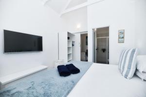 a white bedroom with a large bed with a flat screen tv at Owlet Cottage in Arniston in Arniston