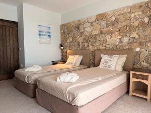 two beds in a room with a stone wall at Luxury villas and golf GV6 in Balchik +21 photos
