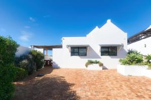 a white house with a brick driveway at Owlet Cottage in Arniston in Arniston