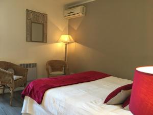 a bedroom with a bed with a red blanket on it at Le Clos Nicolas in Eugénie-les-Bains