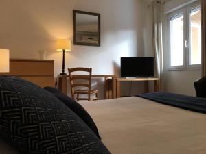 a bedroom with a bed and a desk with a television at Le Clos Nicolas in Eugénie-les-Bains