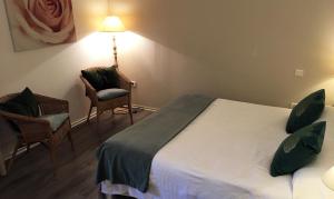 a bedroom with a bed and two chairs and a lamp at Le Clos Nicolas in Eugénie-les-Bains