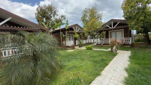 a house with a green yard next to a building at Apella Hotel in Cıralı