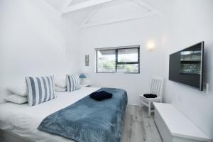 a white bedroom with a bed and a tv at Owlet Cottage in Arniston in Arniston