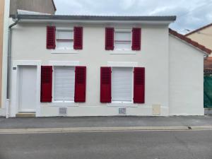 a white building with red shuttered windows on a street at L'Ecrin de Verdun in Verdun-sur-Meuse