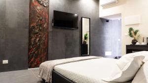 a bedroom with a bed and a tv on a wall at Aetna LuxurySuites in Catania