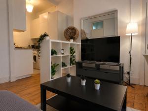 a living room with a table and a flat screen tv at Comfortable 2 Bedroom Flat in Leith in Edinburgh