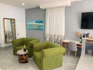 ein Wohnzimmer mit zwei grünen Stühlen und einem Tisch in der Unterkunft Ecolux in Marracuene