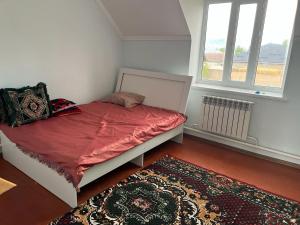 a bedroom with a bed and a rug and two windows at Aimir in Akchiy