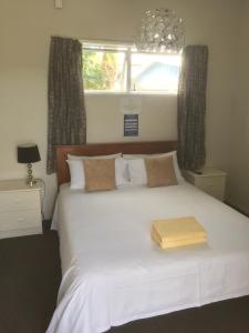 Un dormitorio con una cama blanca con una caja de madera. en Orewa Pillows Lodge, en Orewa