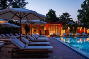 a pool with white lounge chairs and umbrellas at Lill Maison Hotel & City Club in Fethiye
