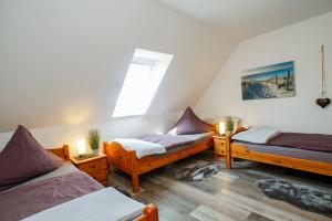a attic room with three beds and a window at Ferien- und Pferdehof Egelkraut "Feriendomizil am Meer" in Wangerland