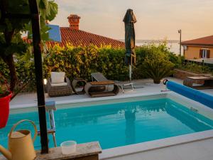 a swimming pool with an umbrella and chairs next to a house at Apartments Apartim Piran in Piran