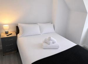 a white bed with a towel on top of it at Large 4-Bedrooms Corporate Flat, Free Parking - Amazing Location in Leavesden Green