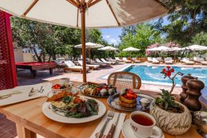 a table with plates of food next to a swimming pool at Lill Maison Hotel & City Club in Fethiye