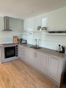 a kitchen with white cabinets and a sink at The Sheep Barn in Weathercote
